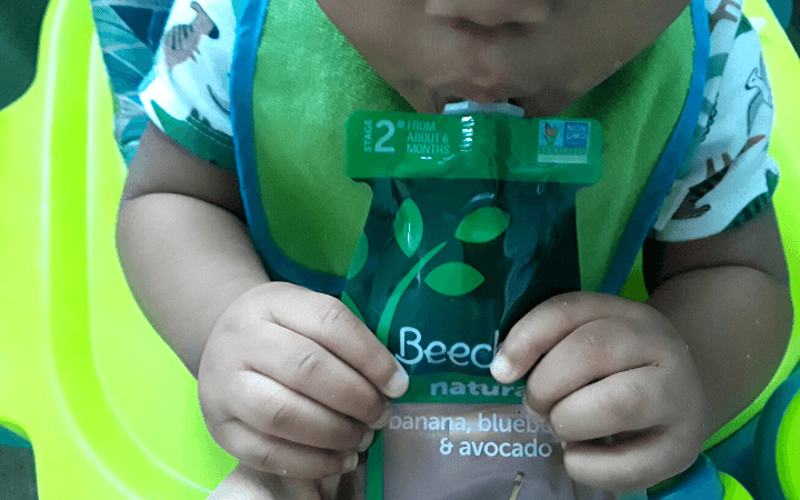 Toddler drinking Beech Nut banana, blueberry,and avocado pouch